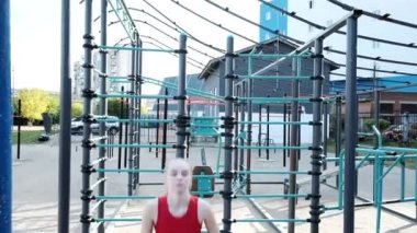 Genç sarışın seksi kadın antrenmanı, spor sahasında çömelme ve zıplama.