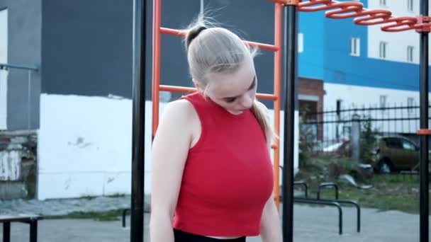 Mladá blondýnka busty žena s culíkem v červené horní natahuje krk na sportovním hřišti — Stock video