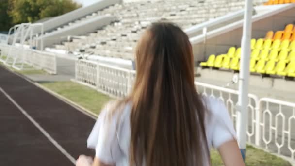 Acompanhamento do jovem corredor de fitness em sportswear correndo na pista do estádio — Vídeo de Stock