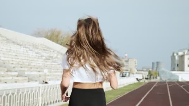 陸上競技場を走るスポーツウェア姿の若きフィットネスランナーのフォローアップショット — ストック動画