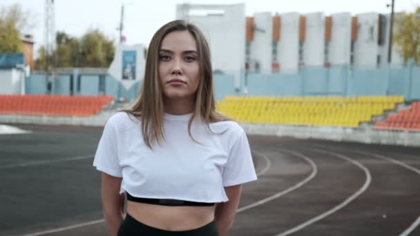 Zâmbind se potrivesc tinere asiatice de sex feminin în îmbrăcăminte sport întinzându-se brațe la stadion sport — Videoclip de stoc