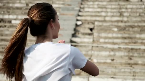 Młoda kobieta w odzieży sportowej rozciągająca ramiona na tle stadionu sportowego — Wideo stockowe