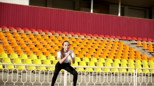 Młody szczupły Azji brunetka kobieta w sportowy odzież robi sportowe ćwiczenia na stadion — Wideo stockowe