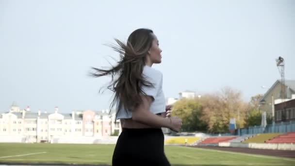 Sottile giovane fitness bella donna corridore in abbigliamento sportivo in esecuzione sulla pista dello stadio — Video Stock