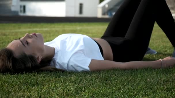 Νεαρή Ασιάτισσα όμορφη γυναίκα με μαύρα κολάν που γυμνάζεται σε εξωτερικούς χώρους στο πράσινο γκαζόν — Αρχείο Βίντεο