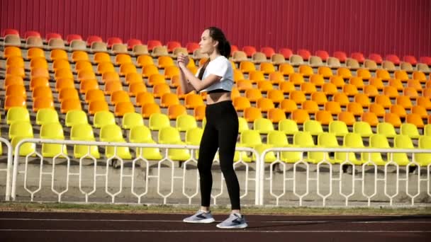 Młody szczupły Azji brunetka kobieta w sportowy odzież robi sportowe ćwiczenia na stadion — Wideo stockowe