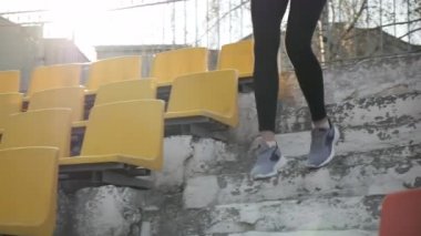 Spor giyim sektöründe genç koşucu stadyumdaki tribün merdivenlerinden inip çıkıyor.
