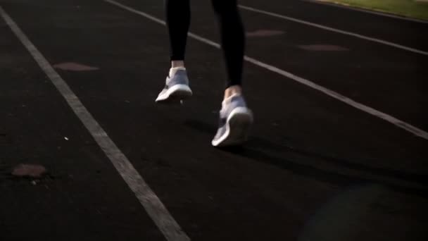 Kolejne ujęcie młodego biegacza fitness w odzieży sportowej biegającego po torze stadionowym — Wideo stockowe