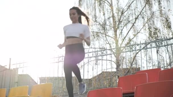 Jeune coureur de fitness en vêtements de sport descendant l'échelle de tribune au stade — Video