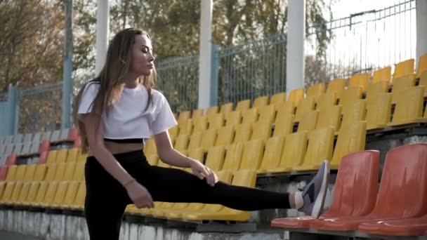 Jeune fit mince asiatique femelle dans sportswear étirement jambes à tribune de stade — Video