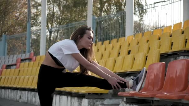 Giovane in forma sottile asiatico femmina in sportswear stretching gambe a tribune di stadio — Video Stock