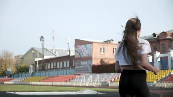 Magro jovem fitness mulher bonita corredor em sportswear correr na pista do estádio — Vídeo de Stock