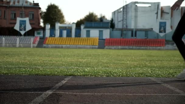 スポーツウェアを着たスリムな白人ランナーが走り始めます。陸上競技場の陸上競技場で — ストック動画