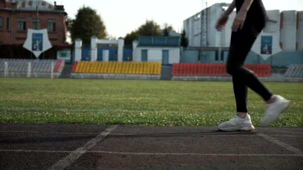 スポーツウェアを着たスリムな白人ランナーが走り始めます。陸上競技場の陸上競技場で — ストック動画