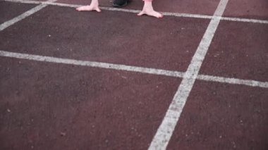 Slim Kafkas spor giyimli koşucu koşmaya başladı. Stadyum pistinde koşuyor.
