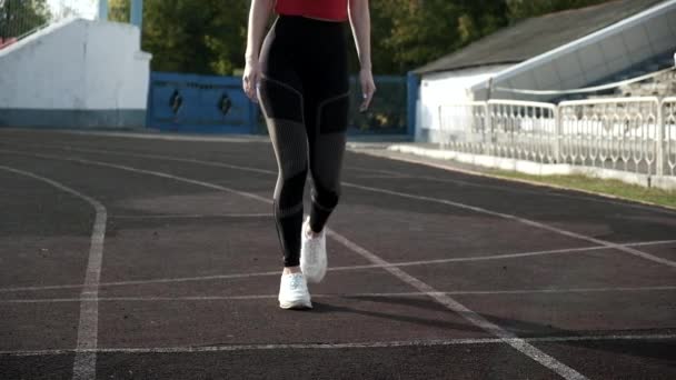 Sottile corridore caucasico in abbigliamento sportivo inizia a correre dal blocco sulla pista dello stadio — Video Stock