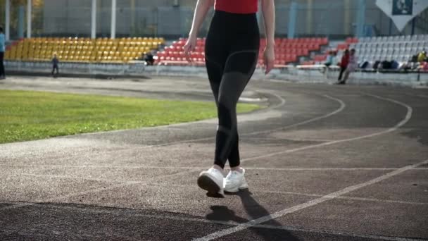 Стройный кавказский бегун в спортивной одежде начинает бегать из блока на стадионной дорожке — стоковое видео