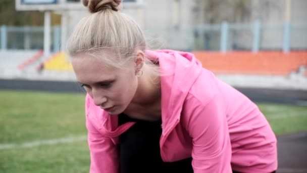 Smal kaukasisk löpare i sportkläder börjar springa. sprintning på stadion spår — Stockvideo