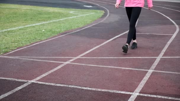 Тонкий бігун у спортивному одязі починає бігати. спринт на трасі стадіону — стокове відео