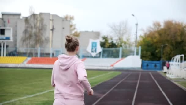 Uppföljning skott av unga fitness löpare i sportkläder som körs på stadion spår — Stockvideo