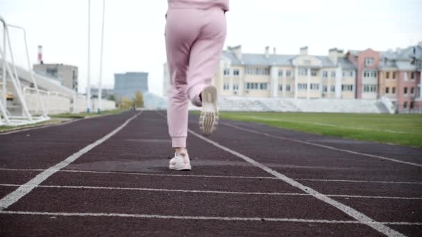 Passar kaukasiska ung kvinna löpare i rosa sportkläder som löper på stadion spår — Stockvideo