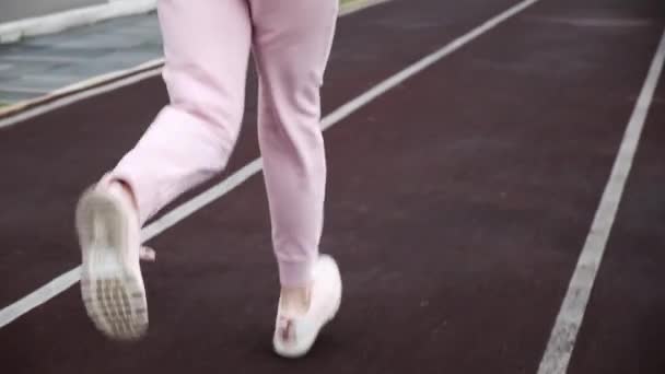 Foto de seguimiento de piernas de corredor de fitness delgadas jóvenes. chica corriendo en pista de estadio — Vídeos de Stock