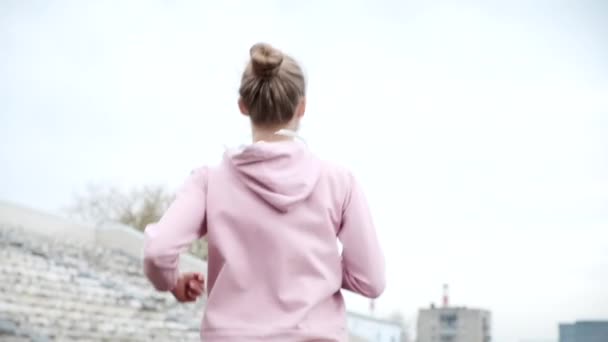陸上競技場を走るスポーツウェア姿の若きフィットネスランナーのフォローアップショット — ストック動画