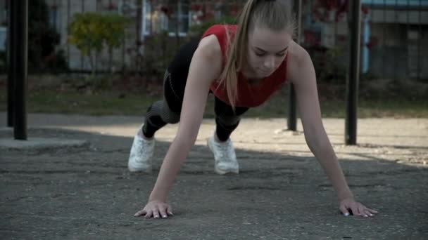 Attrayant caucasien femelle se tient en position de planche au terrain de sport à l'extérieur — Video
