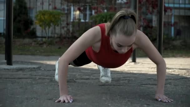 Joven en forma bonita mujer en ropa deportiva hace ejercicios en el campo de deportes al aire libre — Vídeos de Stock