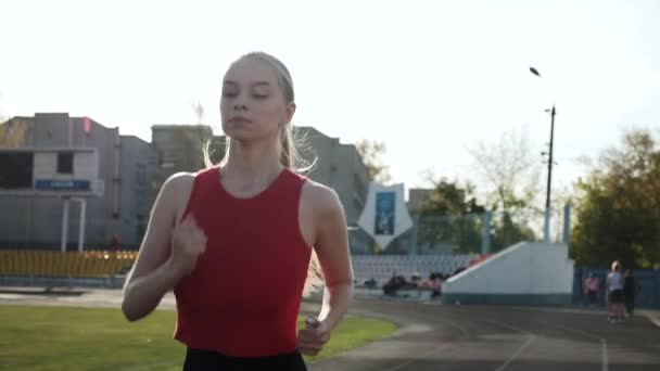 Jovem corredor de fitness caucasiano esportivo em sportswear correndo na pista do estádio — Vídeo de Stock