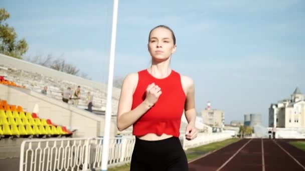 Joven deportista caucásico corredor de fitness en ropa deportiva corriendo en pista de estadio — Vídeos de Stock