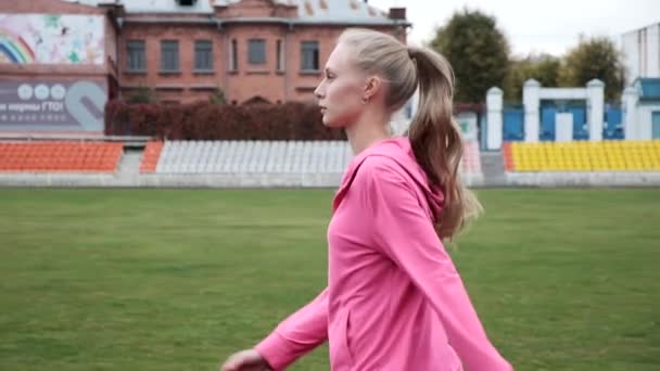 Mladá fit běloška běloška žena ve sportovním oblečení procházky na stadionu, začíná běh — Stock video