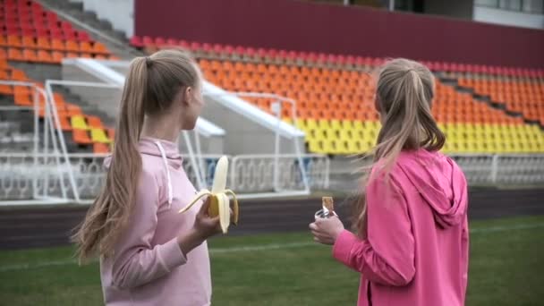 Dos hermanas gemelas idénticas en ropa deportiva rosa en el estadio después del entrenamiento de fitness — Vídeos de Stock