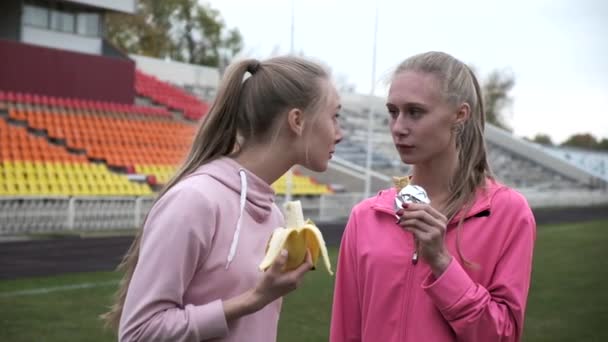 Två identiska tvillingsystrar i rosa sportkläder på stadion efter träning — Stockvideo