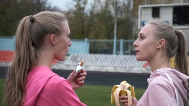 Dos hermanas gemelas idénticas en ropa deportiva rosa en el estadio después del entrenamiento de fitness — Vídeos de Stock