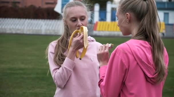 Dos hermanas gemelas idénticas en ropa deportiva rosa en el estadio después del entrenamiento de fitness — Vídeos de Stock