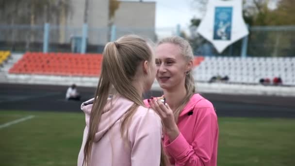 Dua saudara kembar identik dalam pakaian olahraga merah muda di stadion setelah pelatihan kebugaran — Stok Video