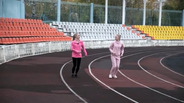 陸上競技場を走るスポーツウェアを着た2人の白人の同じ双子の姉妹 — ストック動画