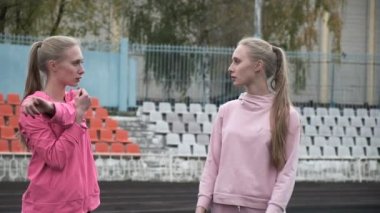 Spor kıyafetleriyle stadyumda kollarını esneten beyaz ikizler.