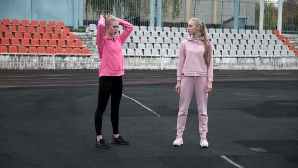 Caucásico idénticos gemelos bonitos en ropa deportiva hacer sentadillas ejercicio en el estadio — Vídeos de Stock