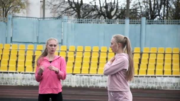 Junge kaukasische eineiige Zwillinge in Sportbekleidung strecken ihre Körper im Stadion — Stockvideo