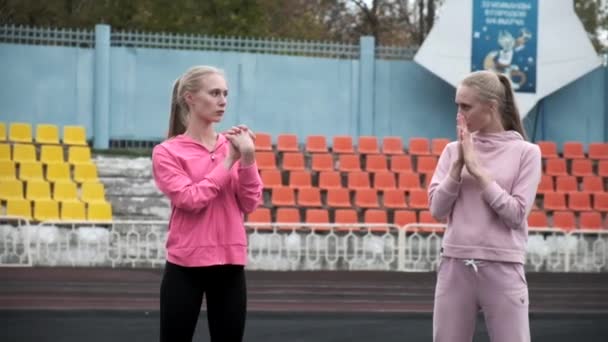 Jovem caucasiano gêmeos idênticos em sportswear esticando as mãos no estádio — Vídeo de Stock