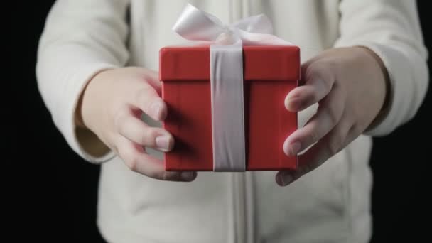 Kleine meisjes handen geven rode geschenkdoos met wit lint. Kerstmis, nieuwjaar — Stockvideo