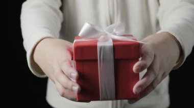 Küçük kızların elleri beyaz kurdeleli kırmızı hediye kutusu veriyor. Noel, yeni yıl