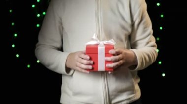 Childs 'ın elleri beyaz kurdeleli kırmızı kutuyu veriyor. Noel, yeni yıl konsepti