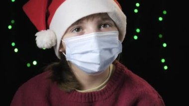 Noel Baba şapkalı kız, tıbbi koruyucu maskeli. Yeni yıl, karantina