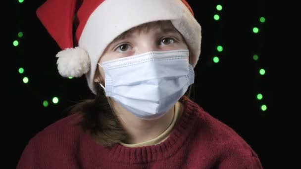 Meisje in de kerstman hoed, medisch beschermend masker. Nieuwjaar, kerst quarantaine — Stockvideo