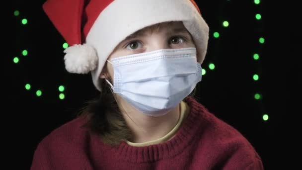 Chica con sombrero de Santa Claus, máscara de protección médica. año nuevo, cuarentena de Navidad — Vídeo de stock