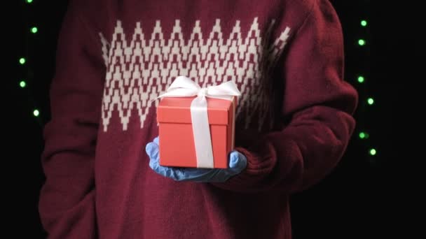 Little childs hand in blue protective gloves giving gift box with white ribbon — Stock Video