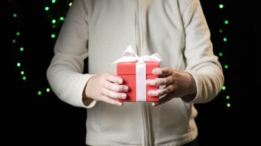 Childs 'ın elleri beyaz kurdeleli kırmızı kutuyu veriyor. Noel, yeni yıl konsepti